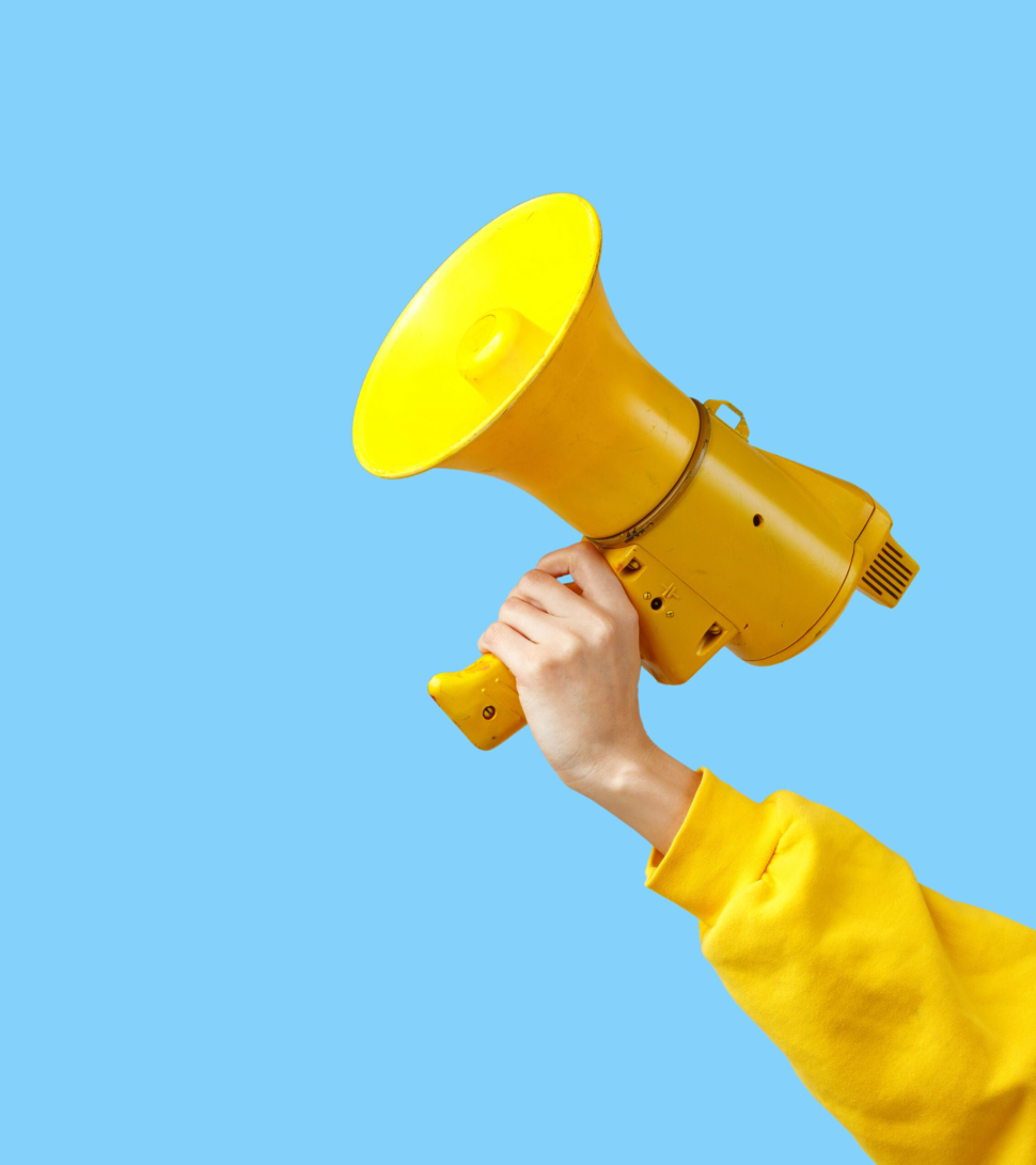 a girl's hand in yellow clothes holds a yellow megaphone on a blue background.